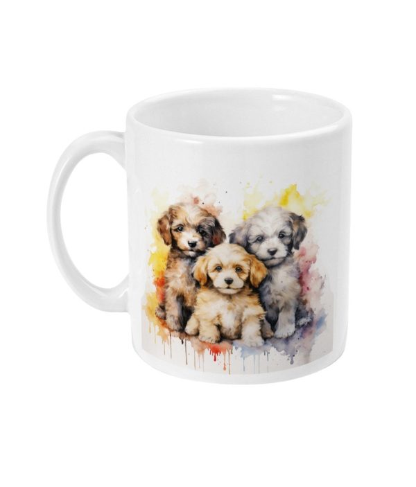 White ceramic mug featuring a watercolor-style graphic of three playful puppies against a colourful backdrop