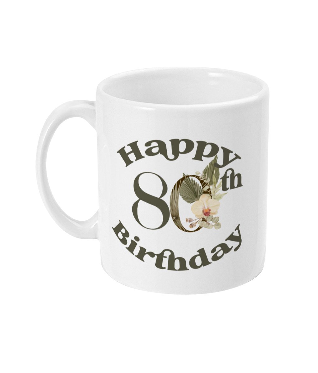 White ceramic mug with 'Happy 80th Birthday' in bold dark gray lettering, surrounded by floral and leaf motifs in green, yellow, and pink.