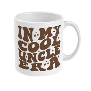 Glossy white ceramic mug with brown 'IN MY COOL UNCLE ERA' text surrounded by playful star shapes.