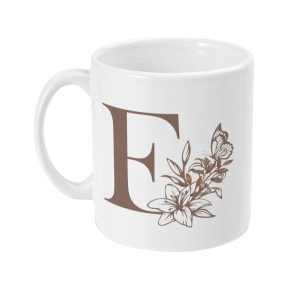 White ceramic mug with a bold brown letter F surrounded by floral designs and a butterfly.