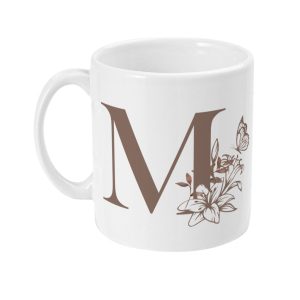 White ceramic mug with large brown 'M' surrounded by floral design and butterfly.