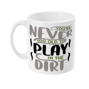 White ceramic mug with text design: 'YOU'RE NEVER TOO OLD TO PLAY IN THE DIRT' in black, green, and gray fonts.